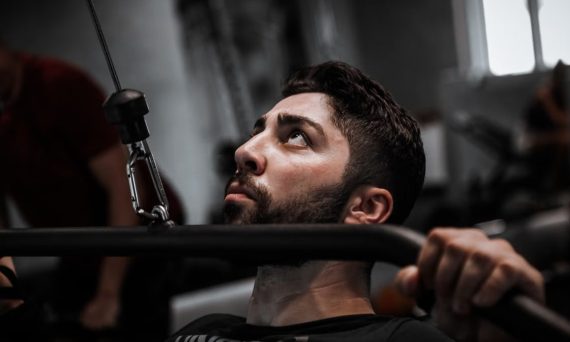 Muscular man working out with determination on gym equipment.